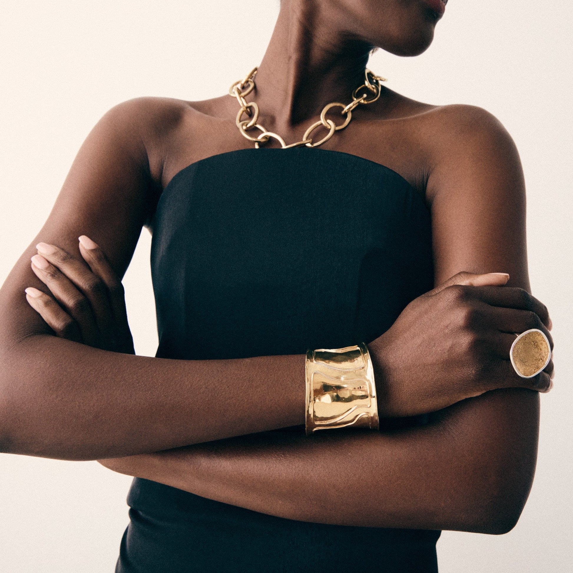Person wearing gold jewelry on a plain background