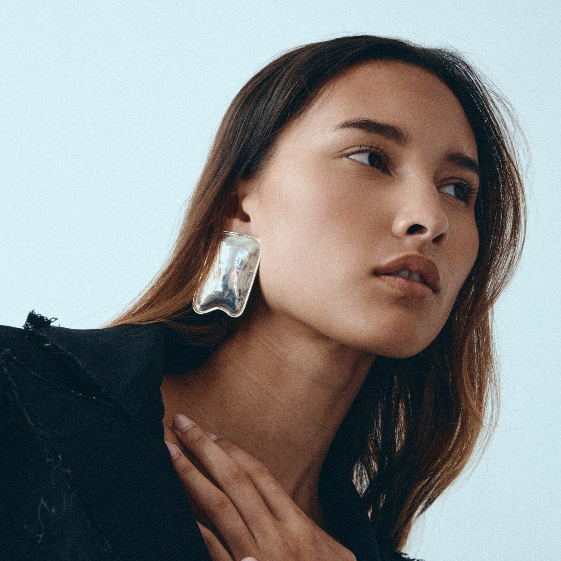 Woman wearing large, clear crystal earrings against a light background