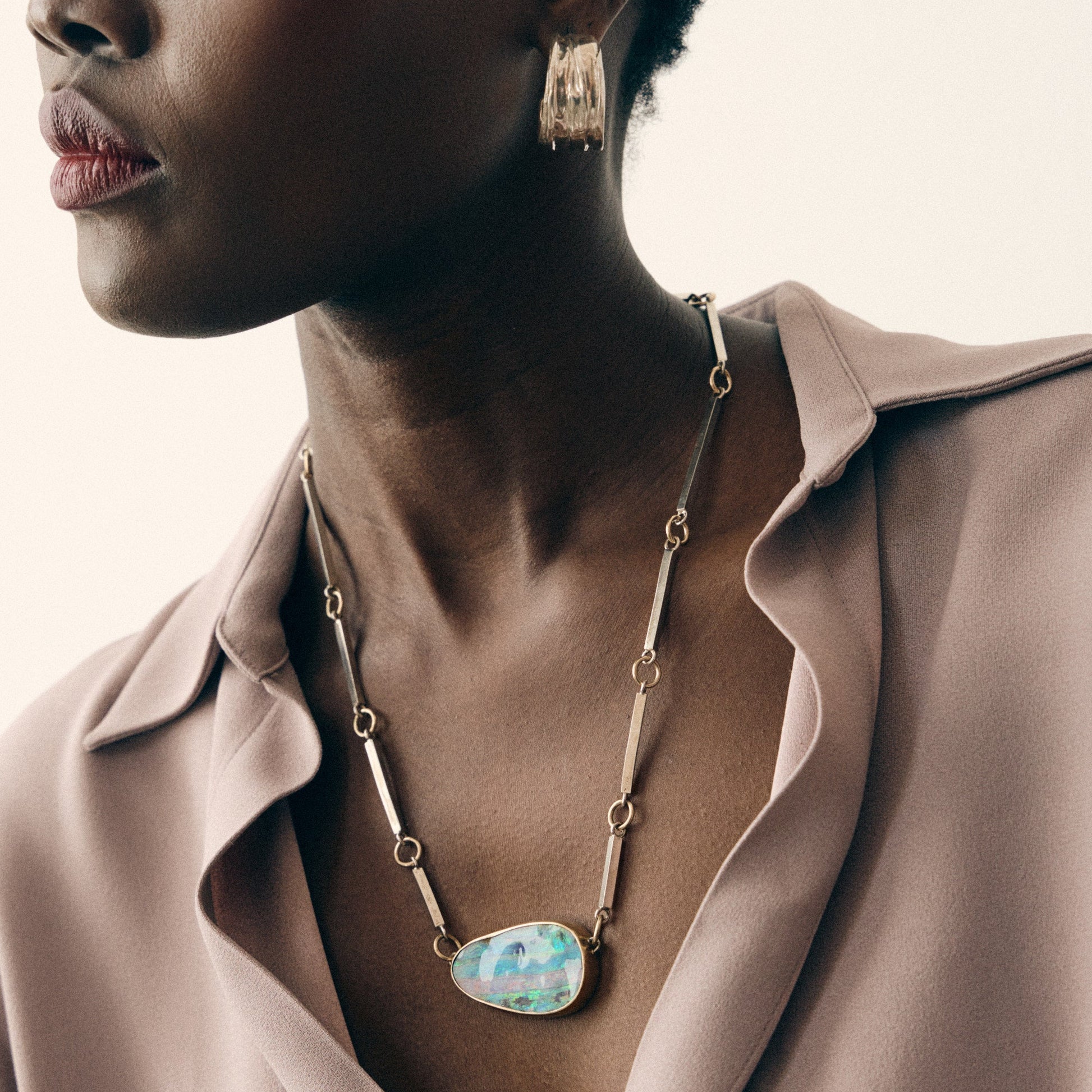 Woman wearing a necklace with a large pendant, close-up of her neck and collarbone.