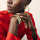Woman wearing gold hoop earrings and a red top against a neutral background
