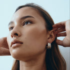 Woman wearing a silver chain necklace and earrings against a light background