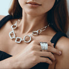 Woman wearing a silver necklace and rings with a neutral background