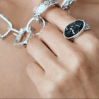 Close-up of a hand wearing silver rings with a blurred background