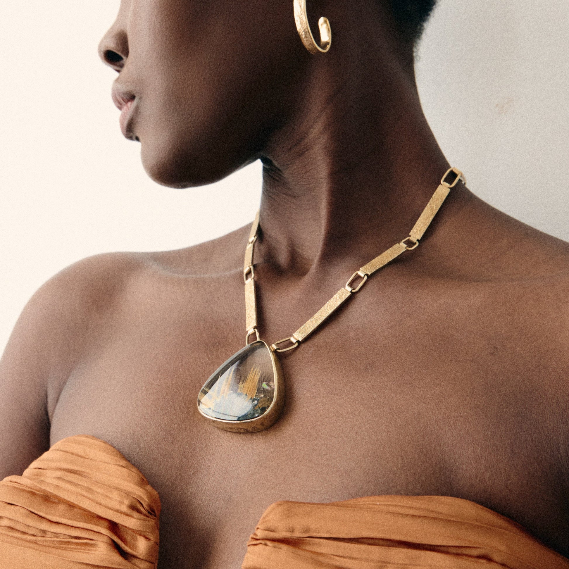 Woman wearing gold jewelry against a neutral background