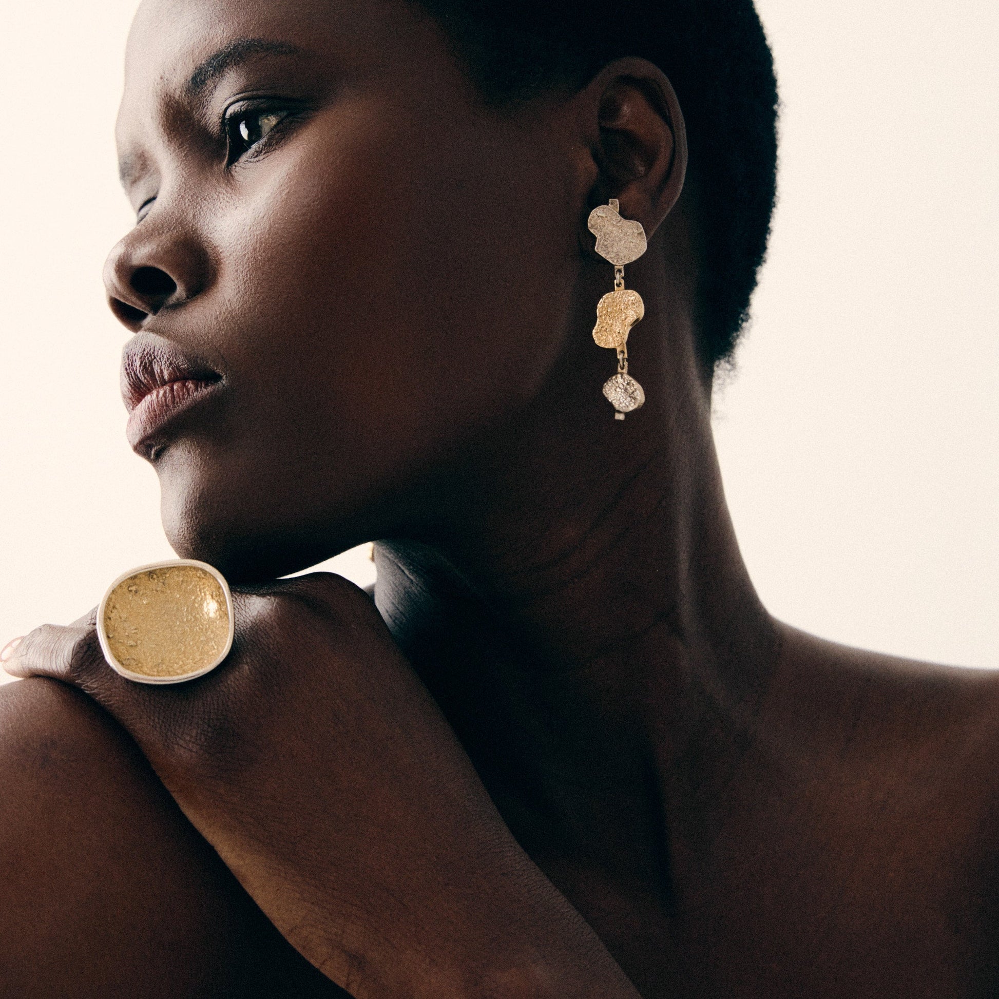 Woman wearing gold earrings with a neutral background