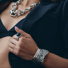 Woman wearing a black outfit with silver jewelry against a light background