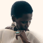 Woman wearing a ring with a large earring, looking down.