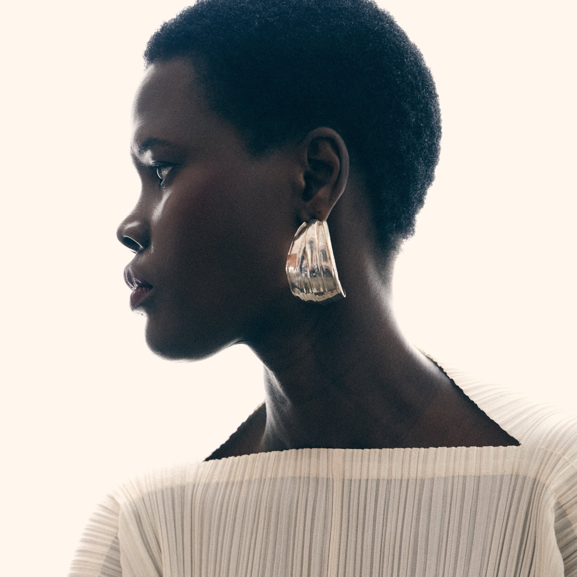 Woman wearing a beige pleated dress with a blurred background