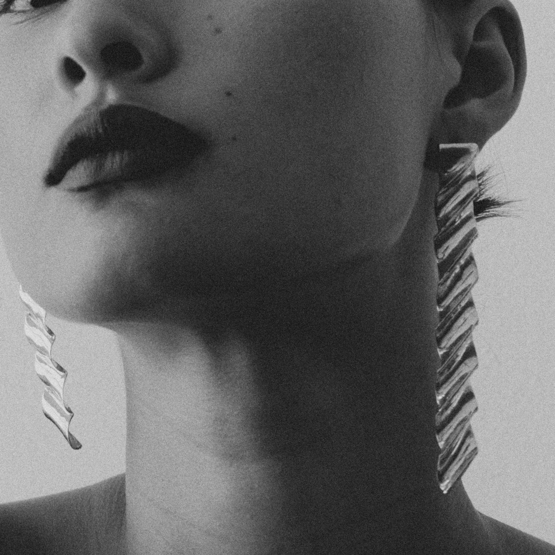 Black and white portrait of a woman wearing large earrings with a neutral background