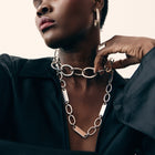 Woman wearing a silver chain necklace with a neutral background