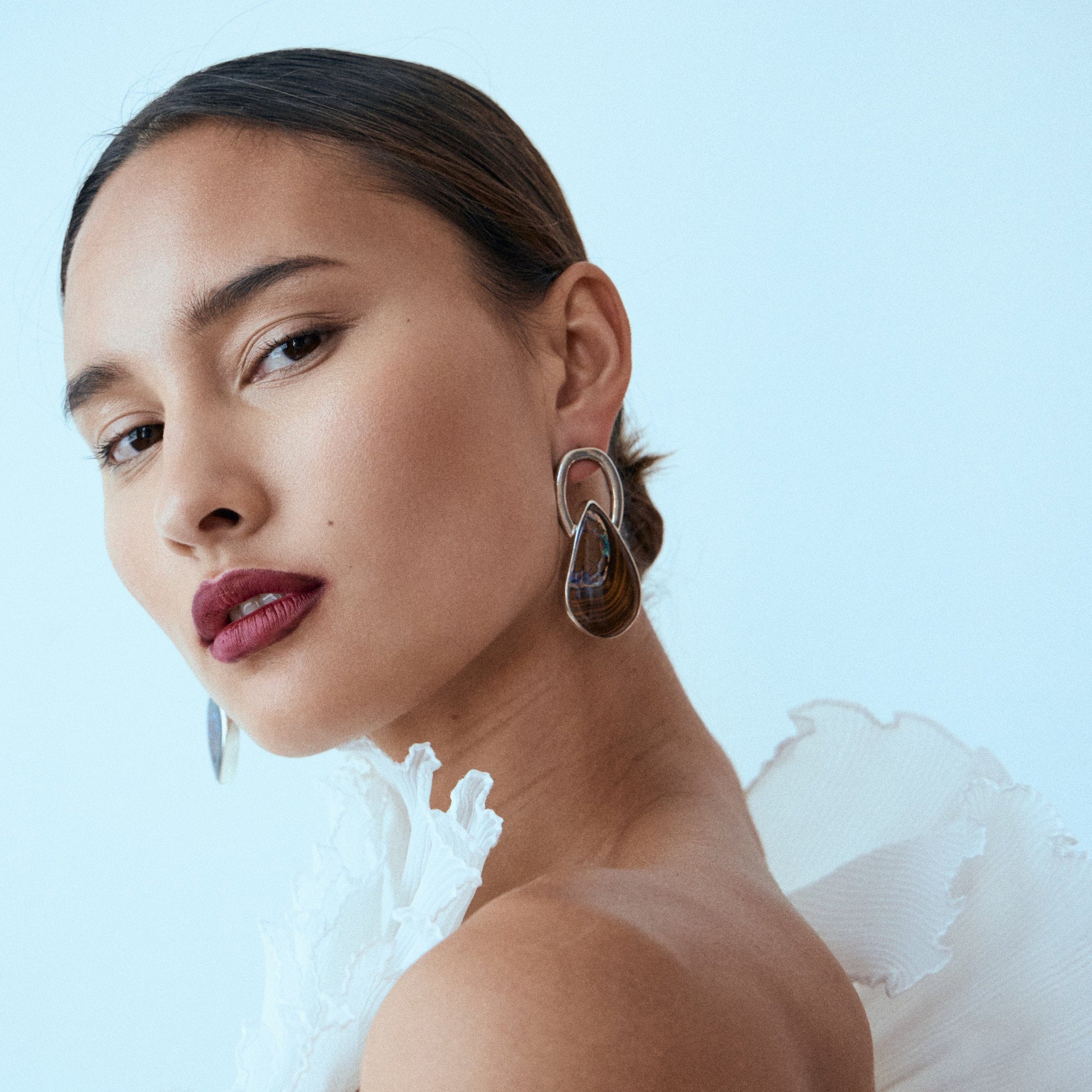Woman wearing large hoop earrings against a light blue background