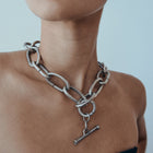Close-up of a person wearing a silver chain necklace with a clasp.