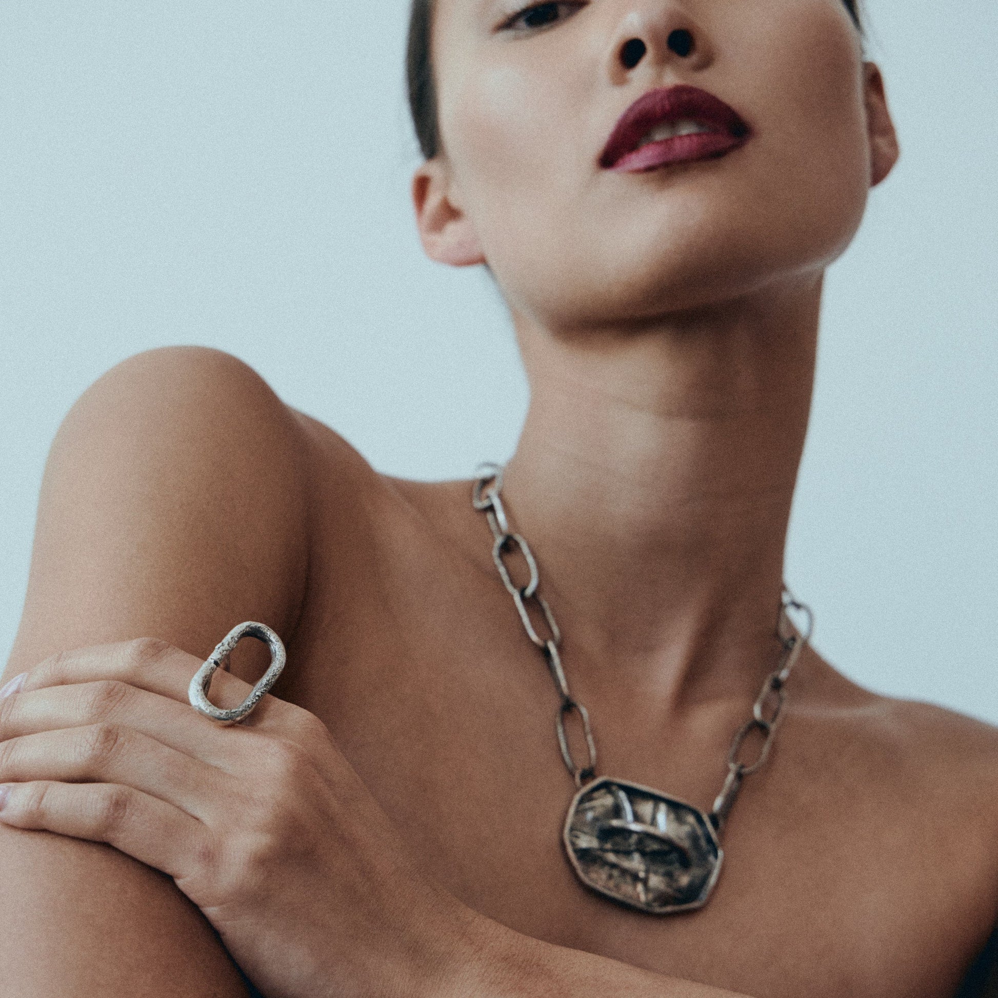 Woman wearing a silver necklace and bracelet against a plain background